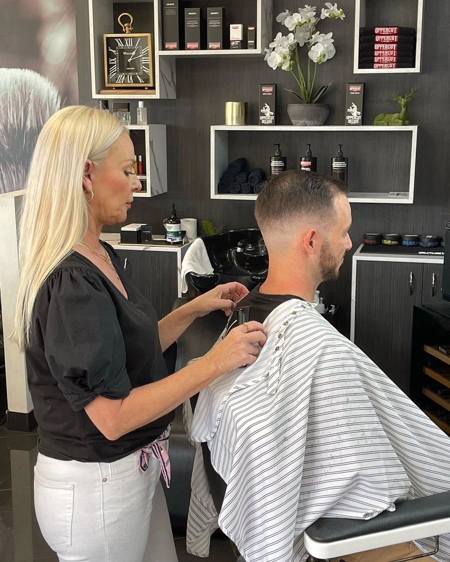 A barber cutting a client's hair on the shop floor at Harry & Boo Barber.