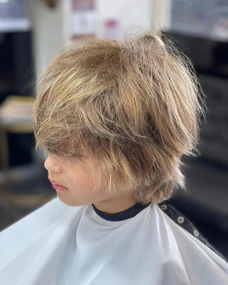 Boy with a longer blonde shaggy cut, layered through the top.