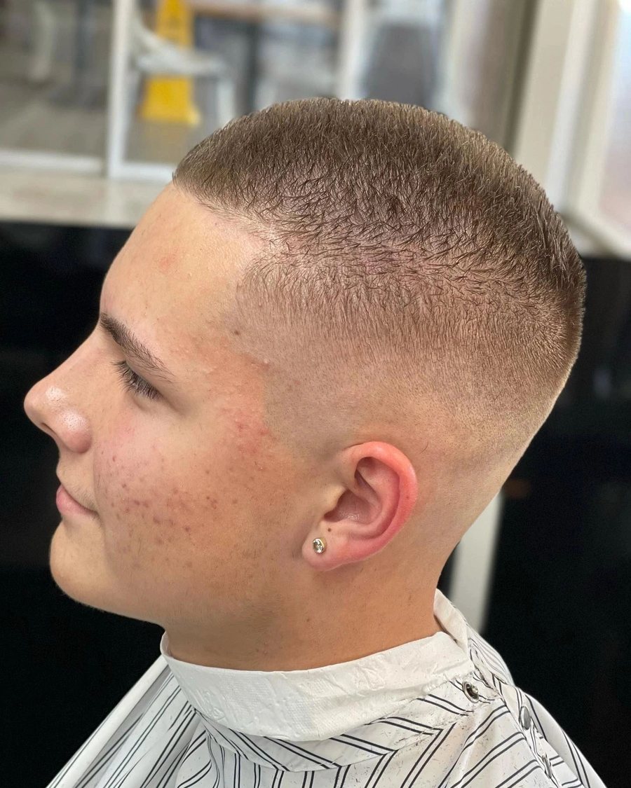 Side profile of a young man with a short crew cut and a high skin fade.