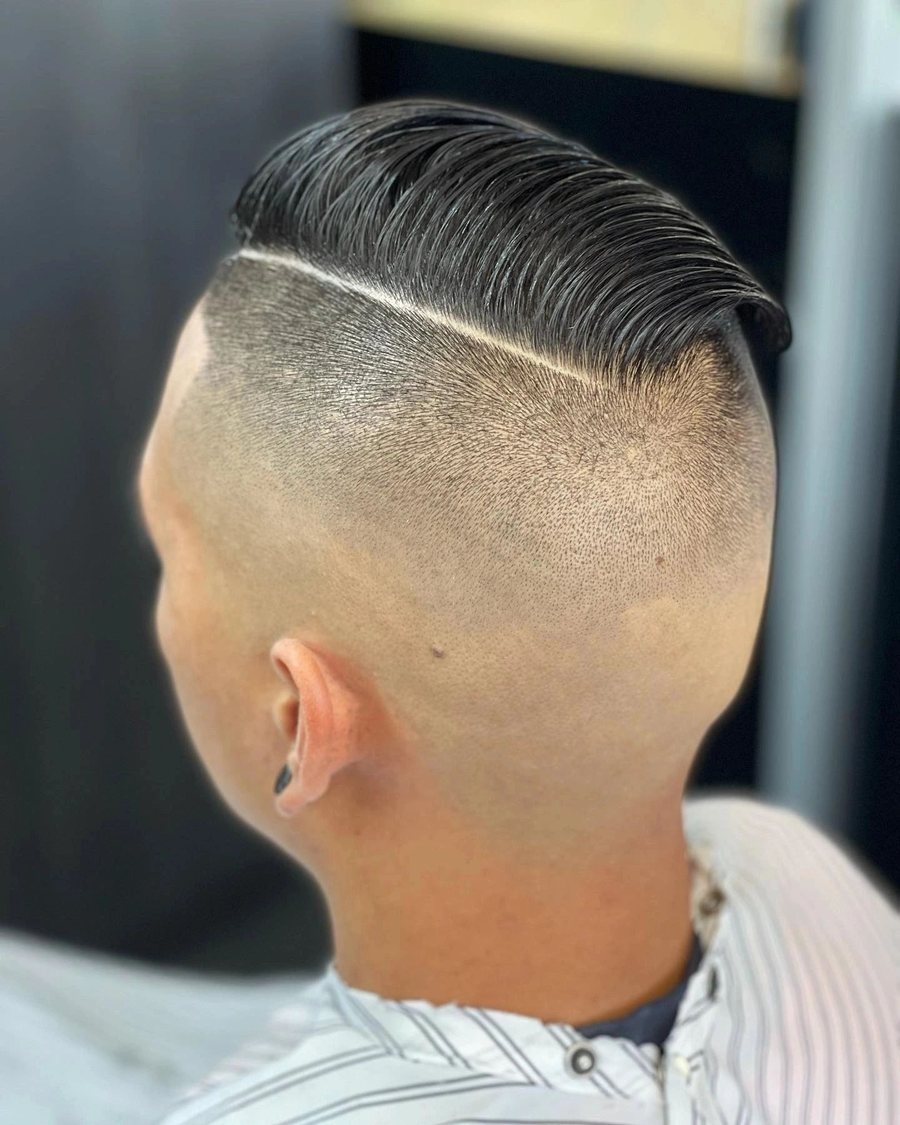 Back three-quarter view of a slicked side part with a hard line and a high skin fade.